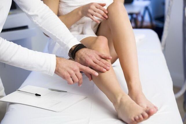 the doctor examines the legs with reticular varicose veins
